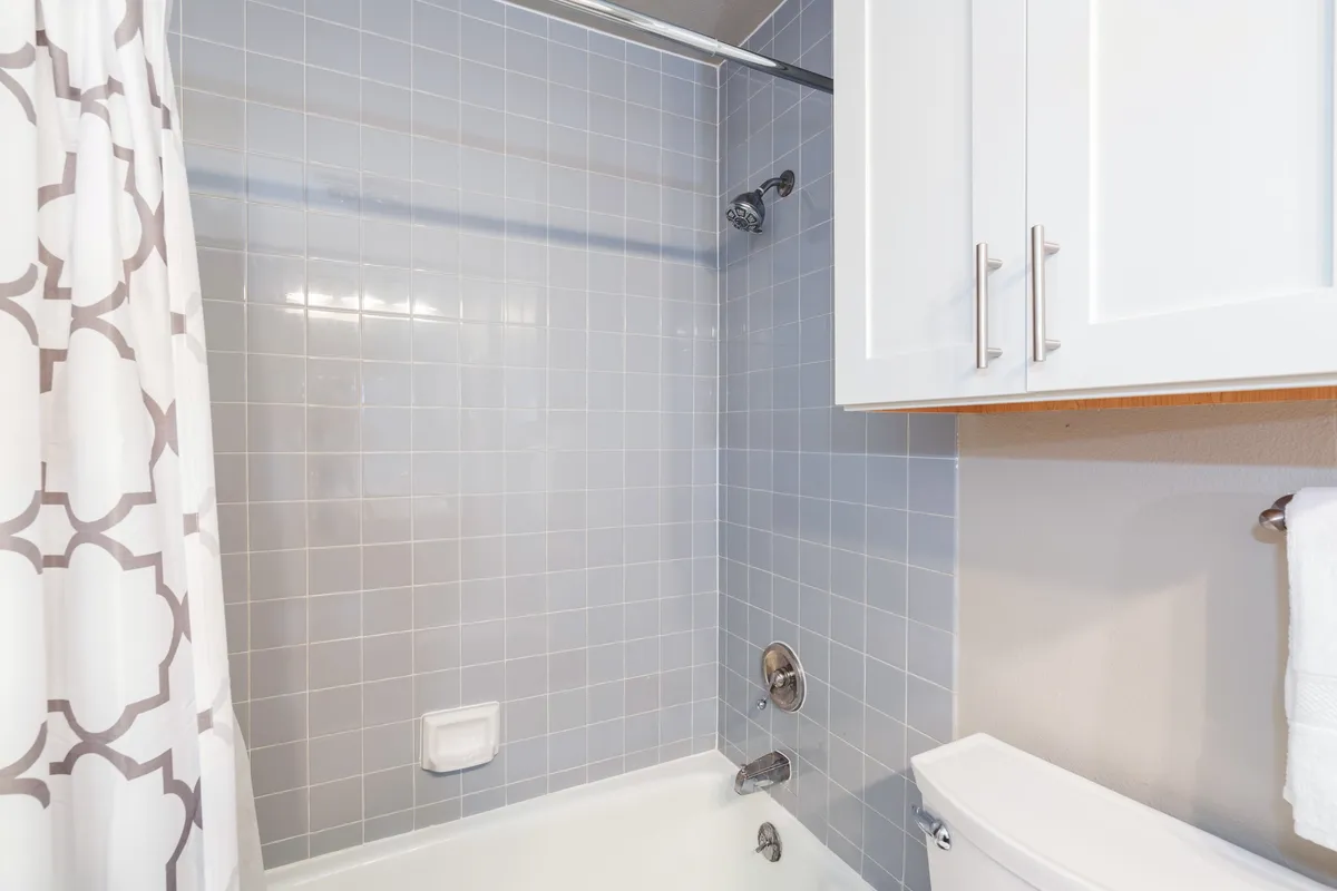 A modern bathroom featuring a tiled shower area, a vanity with storage, and calm, inviting lighting. The space appears clean, well-equipped, and ideal for refreshing after a day outdoors.